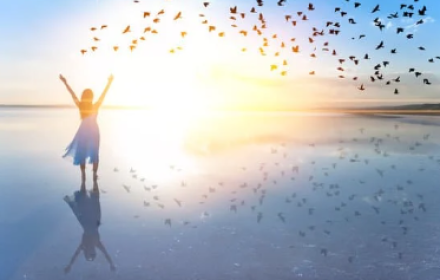 woman in sunset with birds flying around her