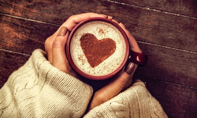 woman's hands holding mug with heart shape art on beverage