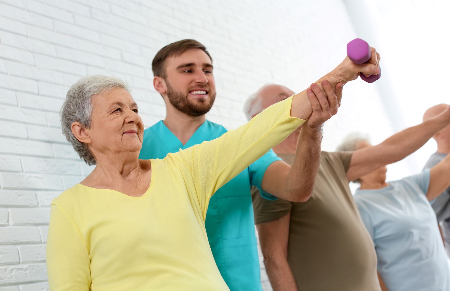 exercise specialist working with elderly with dumbbell