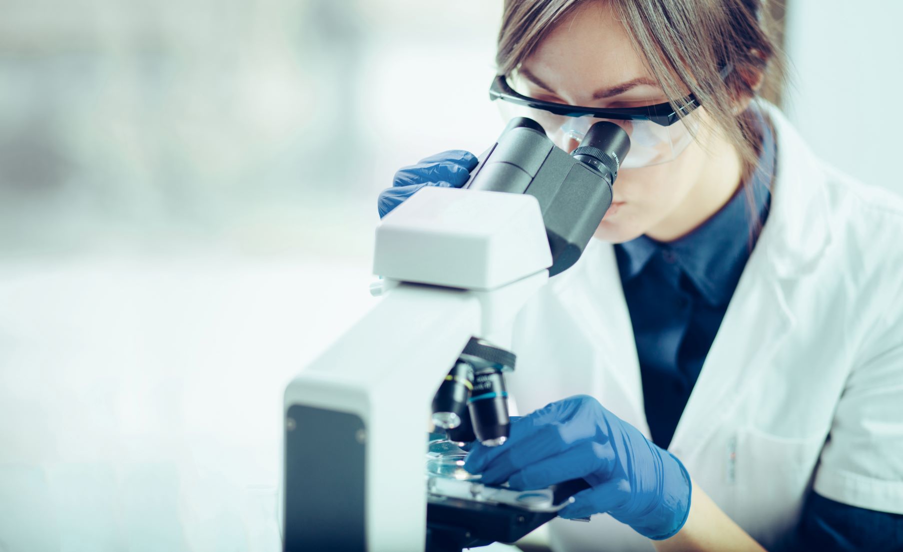 female lab worker looking into microscope