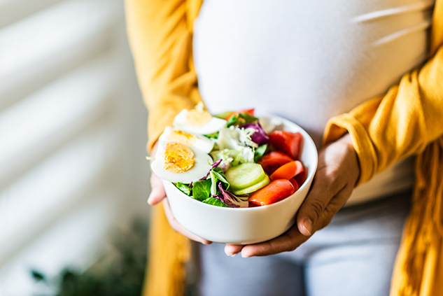 Pregnant woman holding a bowl of salad