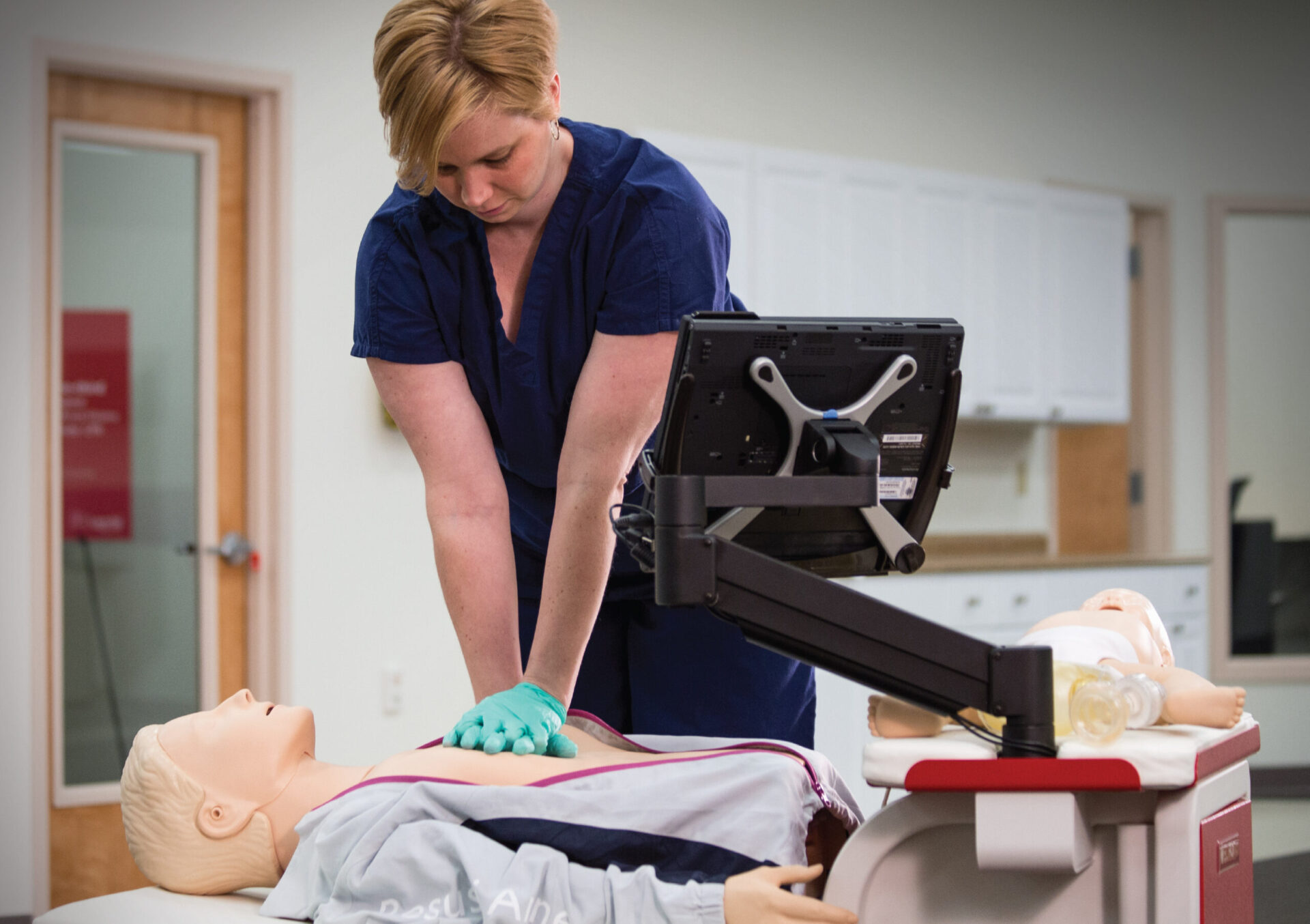 Woman practicing CPR on RQI manikin