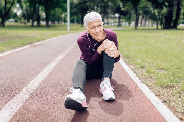 woman sitting on track field holding her knee