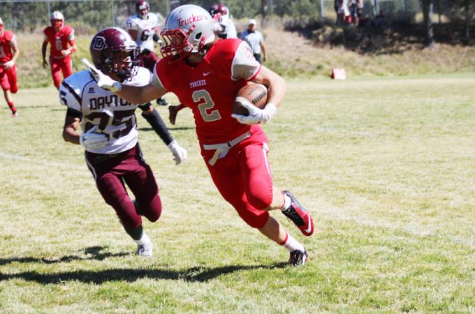 Young football player with ball blocks oncoming defender